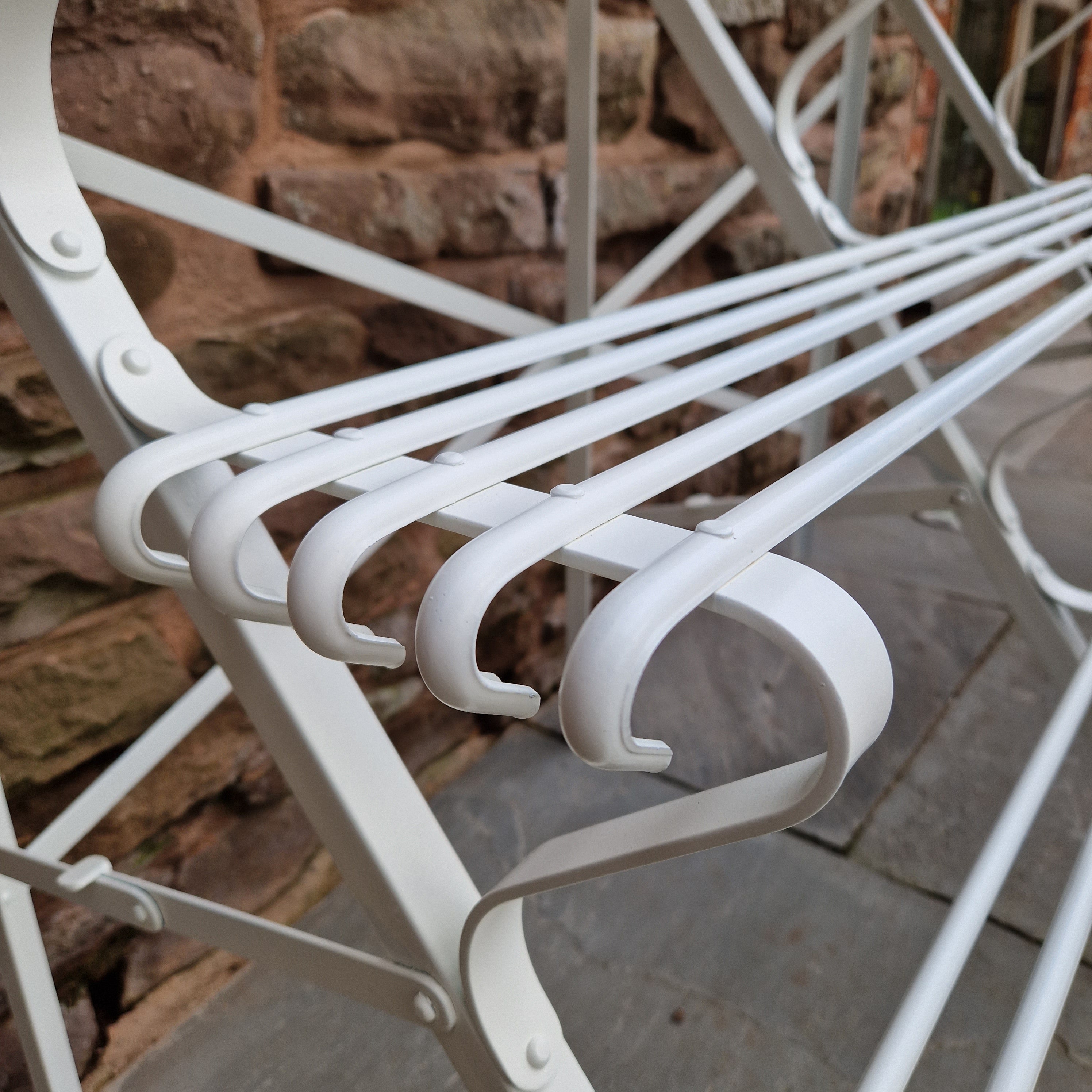 close up of white painted arras style metal plant stand